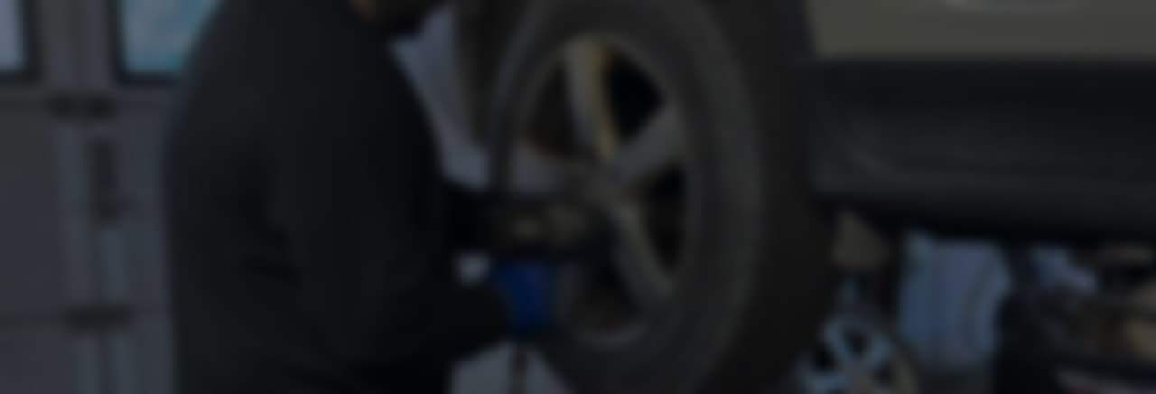 Mekaniker som besiktigar en vit bil i verkstadsmiljö